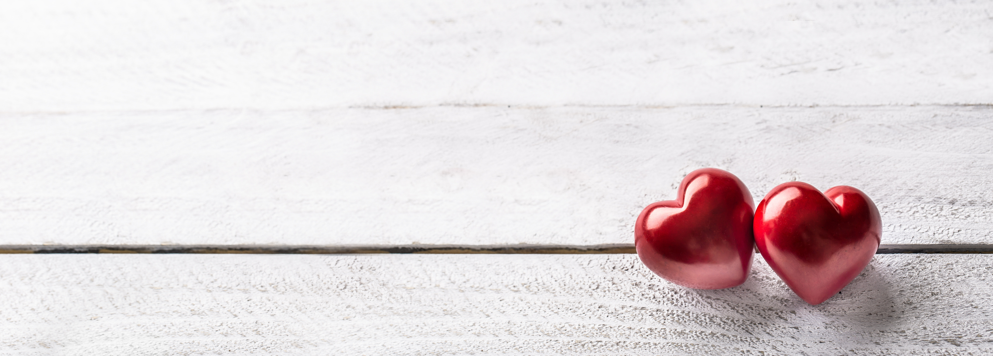 Two red hearts on wooden table. Romantic panoramatic banner for valetines or wedding day.